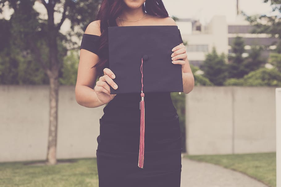 Picture of a lady holding a graduation hat, emphasizing WHY MANY MBAS SWEAR BY THEIR DEGREES